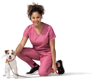 A kneeling woman in a pink outfit pets her terrier