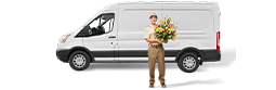 A florist with a bouquet of flowers stands at the side of a white delivery van.