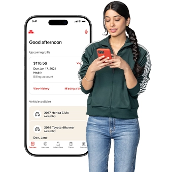 Standing next to an enlarged image of the State Farm app, a young lady with a pigtail and a grey zip-up jacket checks her smartphone.