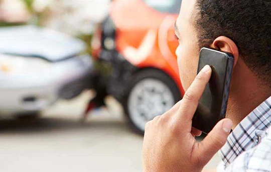 A man on his cellphone watches his car being towed away.