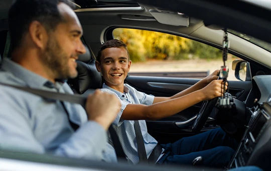 Antes de arrancar el carro, un joven conductor sonríe a su padre, sentado en el asiento del pasajero.