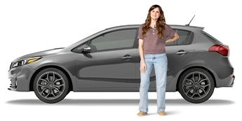 Una joven está parada al lado de su SUV gris con la mano detrás de la espalda. Va vestida con una camisa marrón y jeans azules.