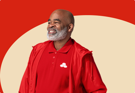 Un agente de State Farm con barba y camisa y chaqueta rojas aparece sonriendo.